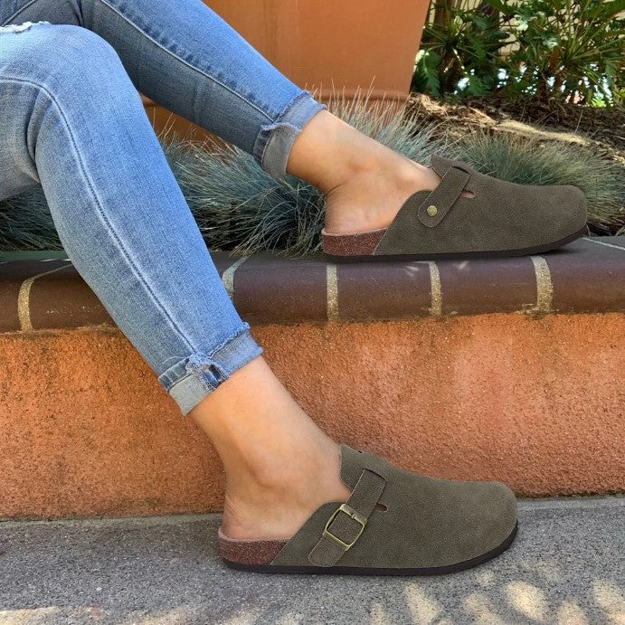 Vrouw met opgerolde jeans draagt bruine suède sandalen met gesp