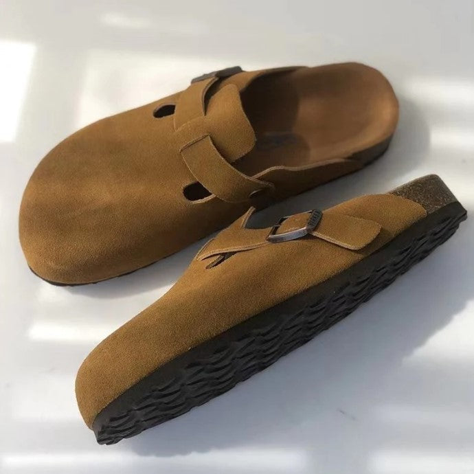 Zijkant van bruine suède sandalen met gesp en zwarte zool